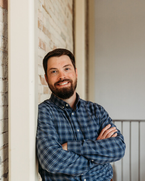 Portrait of a confident male real estate agent standing with arms crossed against a brick wall