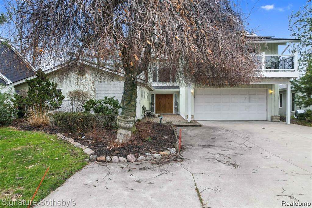 View of property hidden behind natural elements with concrete driveway and a balcony at 2372 Pine Lake Road, West Bloomfield, MI 48324